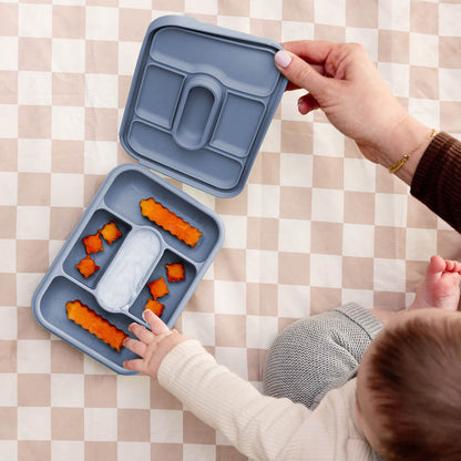ezpz travel box in indigo blue is an all-in-one feeding + storage system that helps families pack, transport, and serve baby’s meals when away from home 